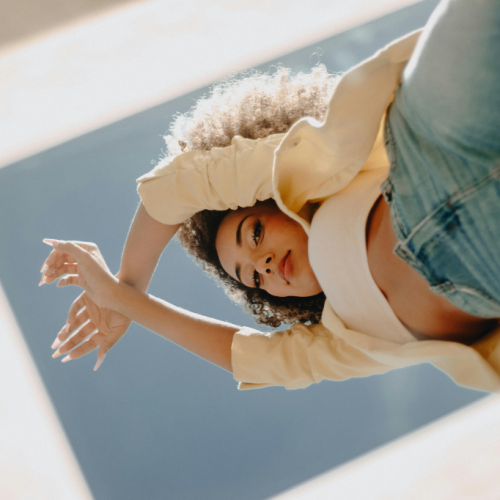 A woman with a mirror on top of her, looking down, reflecting on identity and the signs she's living someone else's life